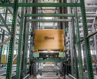 An integrated lift carrying a pallet between racking levels